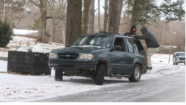 Karen Sanford / The Prentiss Headlight — The hill on Granby Road and old Highway 84 was an icy trap for motorist during the winter storm on Wednesday. Above, men jump on the back bumper of an SUV to help gain traction on the slippery road.